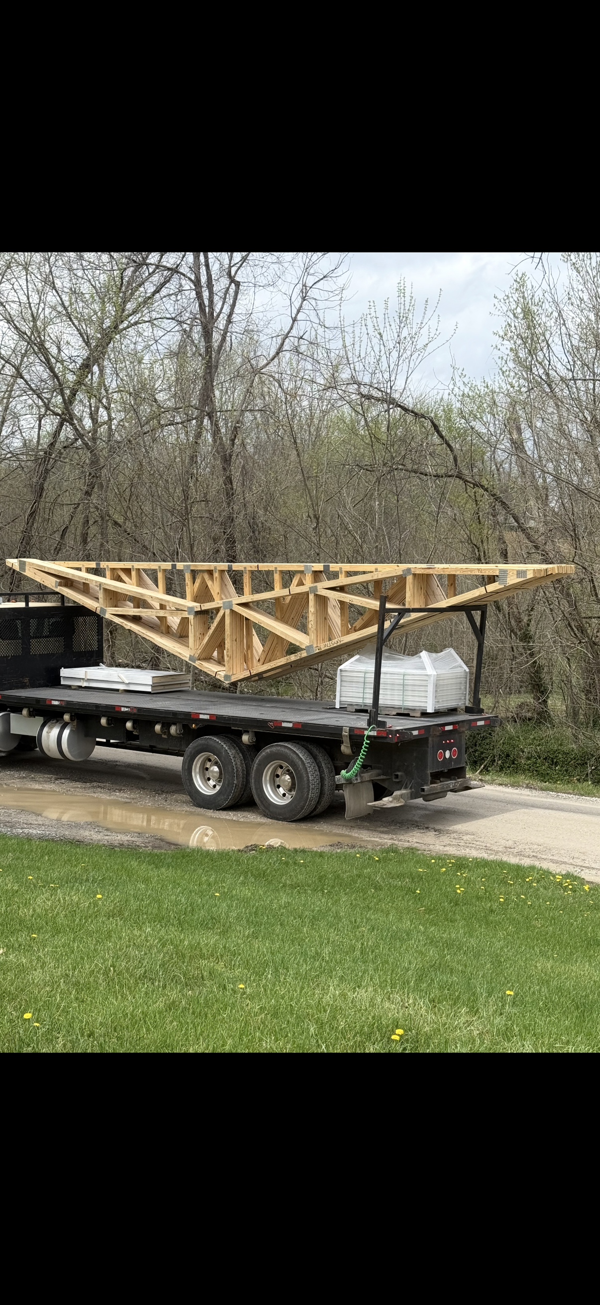 Roof trusses and wood frame house kit materials on flatbed trailer for nationwide delivery